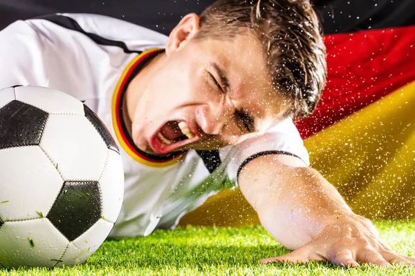 Emocjonujący Młody Mężczyzna Piłkarz Sięgający Piłkę Zielonej Trawie Stadionu Flaga — Zdjęcie stockowe