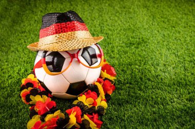 Alman futbol fanatikleri arka planda top, bayrak şapkası ve gözlük takıyor