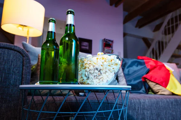 close-up view of beer bottles and popcorn in bowl, soccer ball on couch