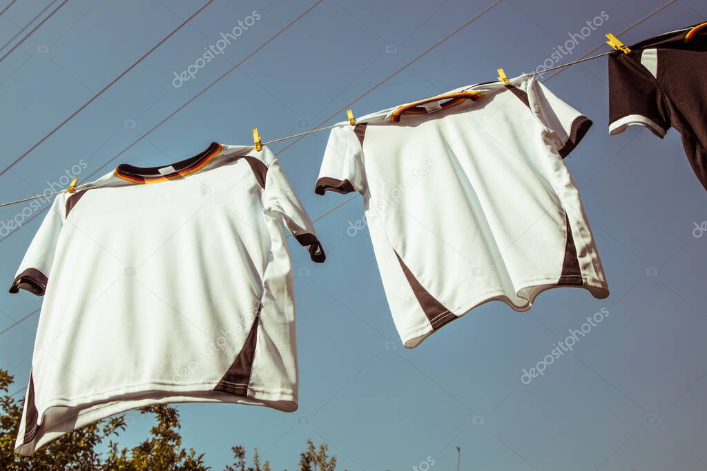 German soccer jerseys hanging in a garden on a clothesline on a summer day. Soccer championship concept 