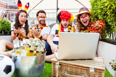 Bir grup hevesli Alman futbol fanatiği dizüstü bilgisayarla futbol maçı izliyor.