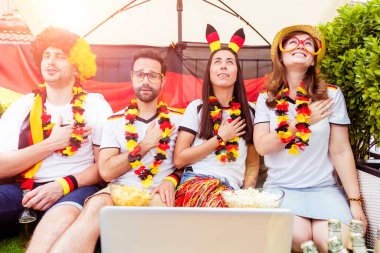 Bir grup hevesli Alman futbol fanatiği dizüstü bilgisayarla futbol maçı izliyor.