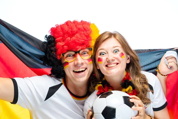 couple of enthusiastic German sport soccer fans celebrating victory, holding soccer ball and German flag