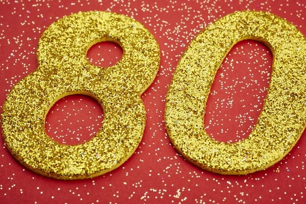 Número oitenta cor dourada sobre um fundo vermelho. Aniversário — Fotografia de Stock