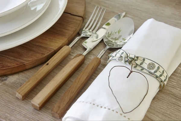 Cuchara tenedor cuchillo y vajilla sobre una mesa rústica — Foto de Stock