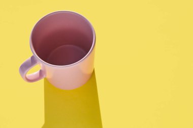 Sarı arka planda pembe kupa. Sabah kahvaltısı. Tasarım porseleni