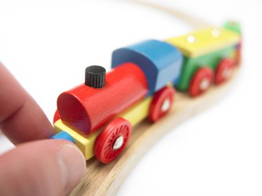 Renkli ahşap oyuncak tren üzerinde beyaz izole el ile