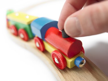 Renkli ahşap oyuncak tren üzerinde beyaz izole el ile