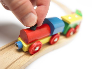 Renkli ahşap oyuncak tren üzerinde beyaz izole el ile