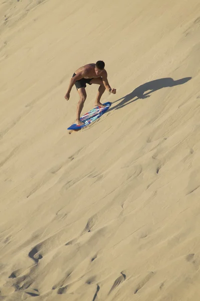 Genç adam sandboarding bir kumul içinde. İspanyol sahil şeridi. Cadiz