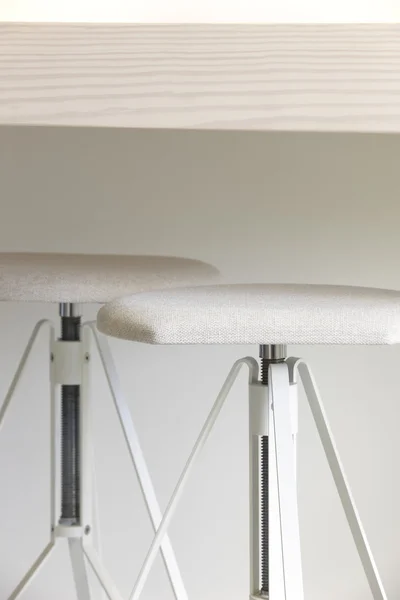 White stools with wooden table and a wall — Stock Photo, Image