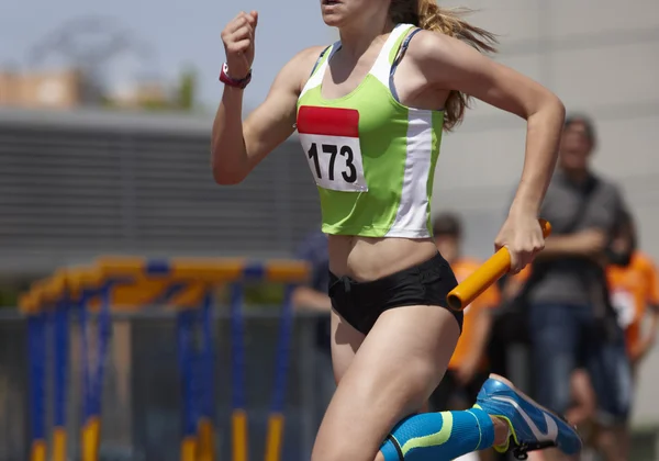 Femmina corridore finalizzare una gara staffetta in una pista di corsa — Foto Stock