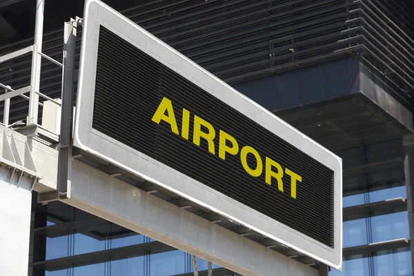 Segnaletica aeroportuale in città con facciata di sfondo edificio — Foto Stock