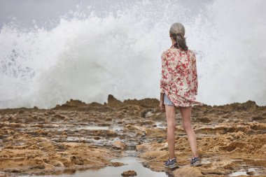 Denize bakan yaşlı kadın. Sahilde dalgalar kopuyor