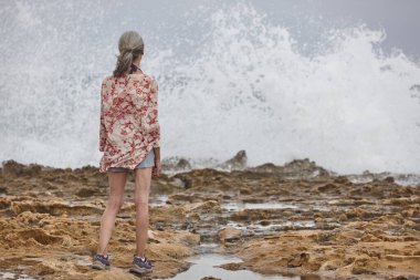 Denize bakan yaşlı kadın. Sahilde dalgalar kopuyor