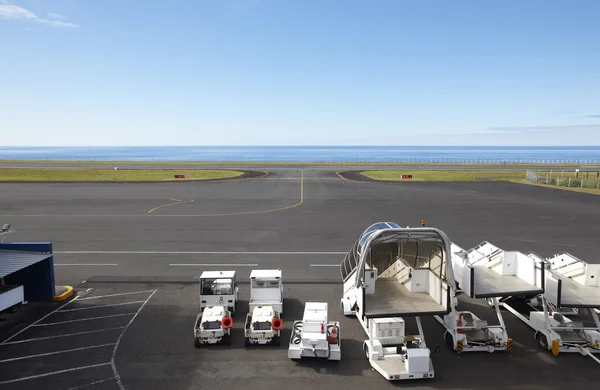 Pista de aterrizaje cerca del océano con vehículos auxiliares — Foto de Stock