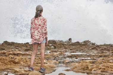 Denize bakan yaşlı kadın. Sahilde dalgalar kopuyor