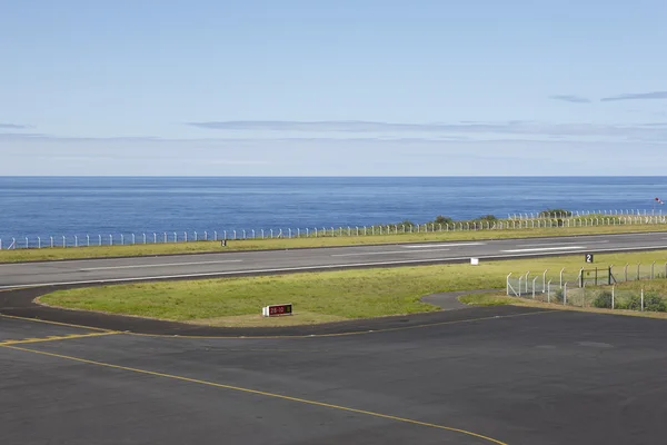 ВПП аэропорта рядом с океаном с линиями и забором — стоковое фото