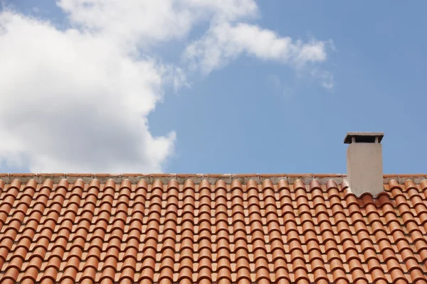 Telhado telha laranja com chaminé sobre um céu azul — Fotografia de Stock