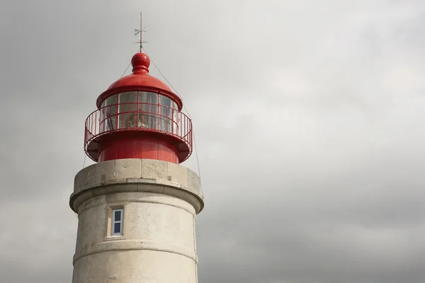 Stone lighthouse with metallic red dome on a cloudy day — Stock Photo, Image