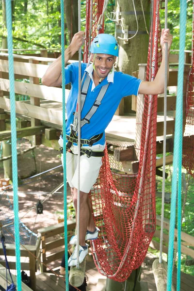 Homem sobe sobre obstáculos em quadra de corda alta — Fotografia de Stock