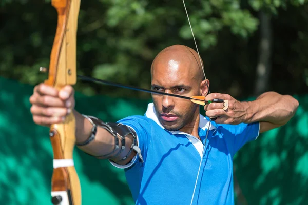 Archer apontando para o alvo com arco e flecha — Fotografia de Stock