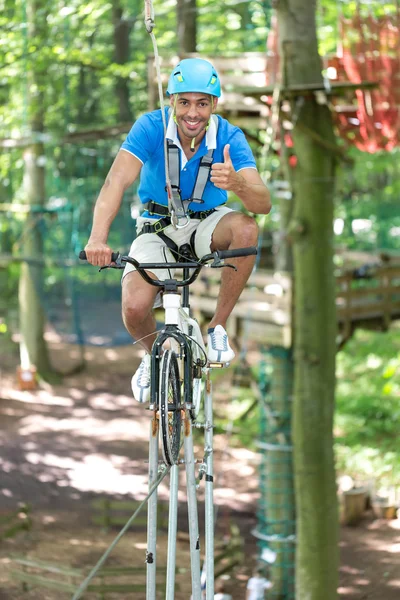 Man rider cykel på balansgång på hög rep kurs — Stockfoto