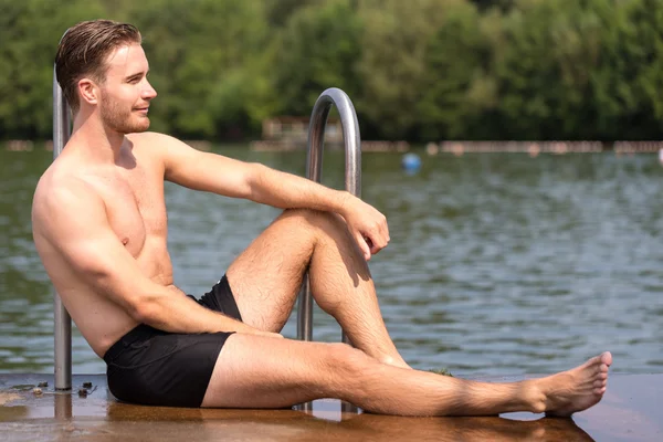 Мужчина расслабляется на солнце в общественном бассейне — стоковое фото
