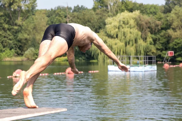 Homme sautant du plongeoir à la piscine — Photo