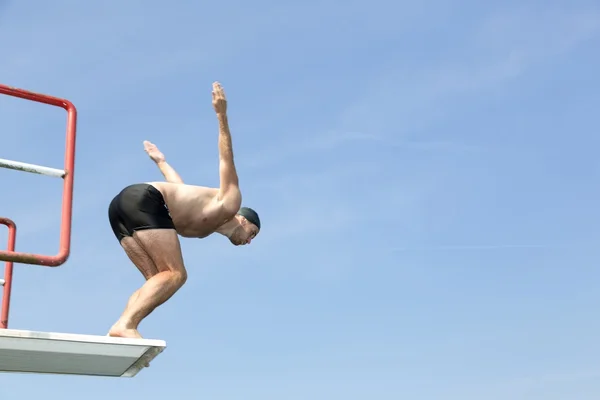 Man jumping off diving board at swimming pool Stock Image