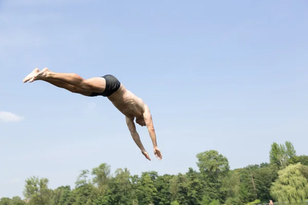 Man jumping off diving board at swimming pool Stock Picture