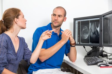 Radiologist councelling a patient using images from tomograpy or MRI clipart