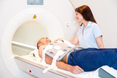 Medical technical assistant preparing scan of torso with MRI clipart