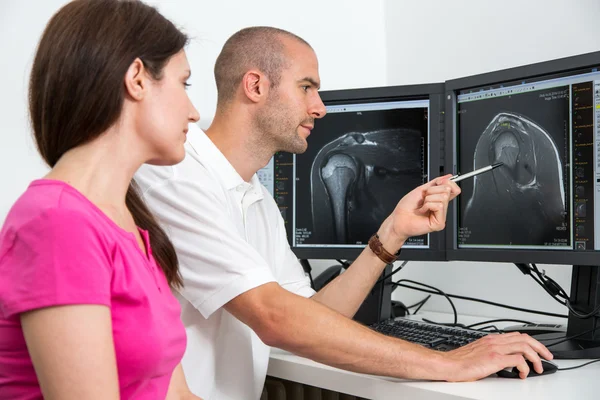 Radiólogo aconsejando a un paciente usando imágenes de tomografía o resonancia magnética Fotos de stock libres de derechos