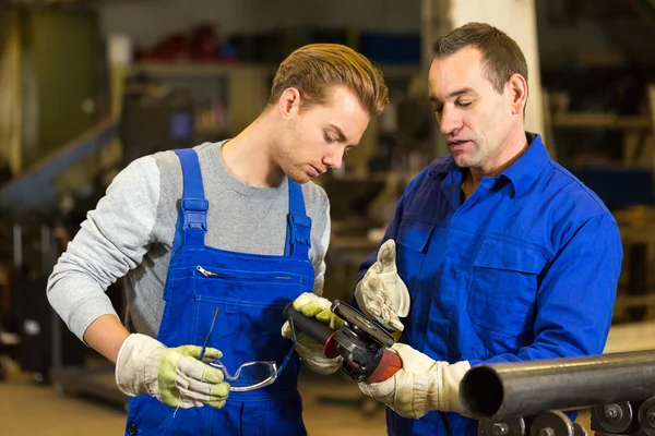 Instrutor ensina trainee como usar um moedor de ângulo — Fotografia de Stock