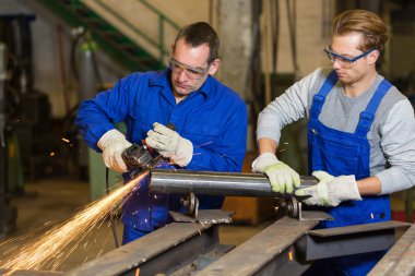 İki işçilerin açı öğütücü ile çalışma