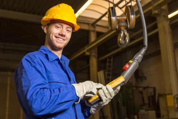 Construction worker operating crane in assembly hall — Stock Photo, Image