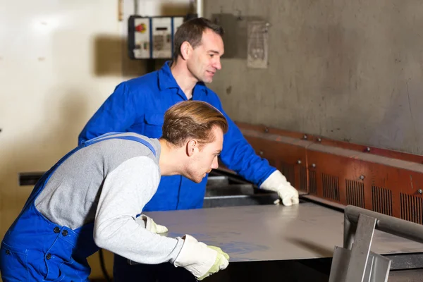 Two workers bending sheet metal with large machine — Stock Photo, Image
