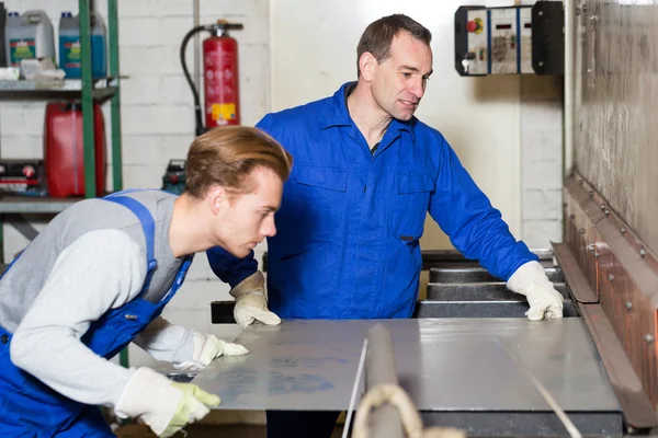 Two workers bending sheet metal with large machine — Stock Photo, Image