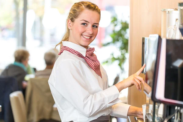 Serveerster werkzaam bij koffiemachine in bakkerij of café — Stockfoto