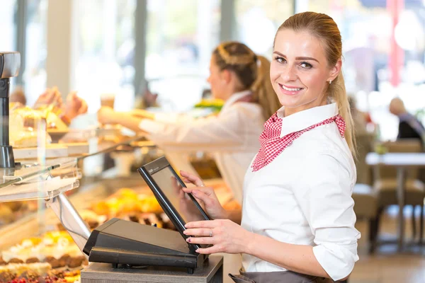 Shopkeeper at bakery working at cash register — Stock Photo, Image