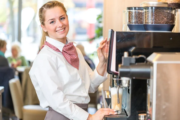 Serveerster werkzaam bij koffiemachine in bakkerij of café — Stockfoto