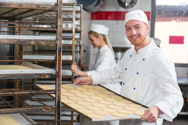 Baker presenteren lade met gebak of deeg in bakkerij — Stockfoto