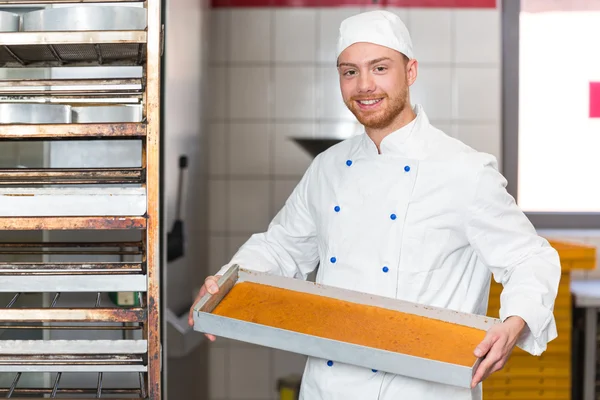Bäcker präsentiert Blech mit frischem Teig in Bäckerei — Stockfoto