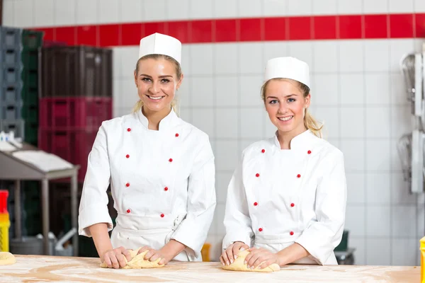 Two female bakers in bakery kneading dough at bakery — Stock Photo, Image