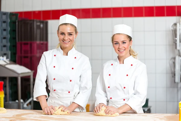 Due panettieri femminili in pasticceria impastano la pasta a pasticceria — Foto Stock