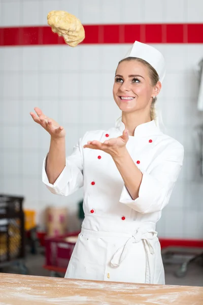 Baker at bakery throwing dough up in the air — Stock Photo, Image