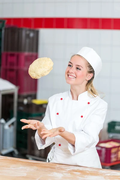 Baker in bakkerij deeg overgeven in de lucht — Stockfoto