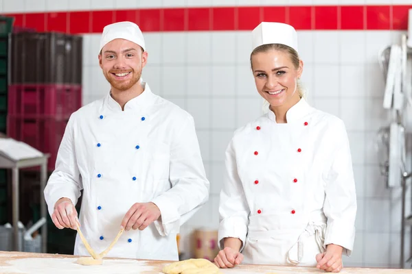 Instrutor e aprendiz na padaria fazendo pretzels — Fotografia de Stock