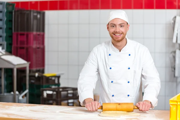 Baker met deeg rollen werkt in een bakkerij — Stockfoto